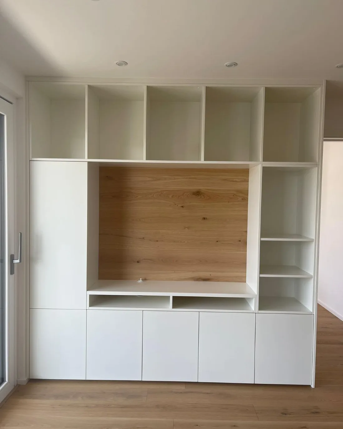 Weiße Einbau-Wohnwand mit offenen Fächern und TV-Nische aus Eiche