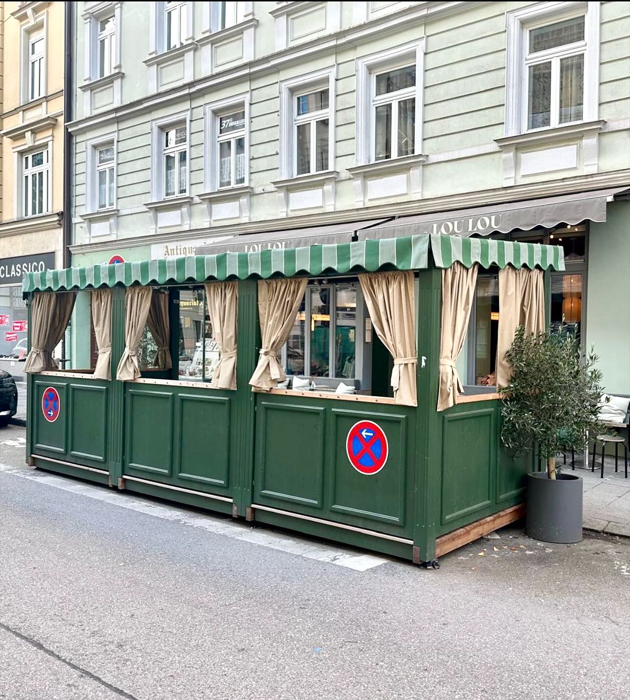 Fertiger Schanigarten für Lou Lou in München — grüne Einfassung mit Markise